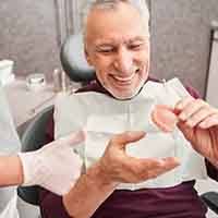 a patient smiling while receiving his new dentures