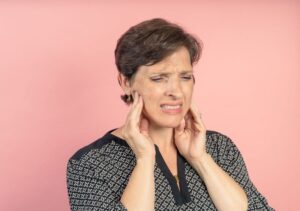 Grimacing woman massaging sides of her face